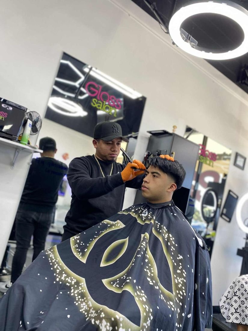 Luis cortando el cabello a un cliente en Gloss Salon